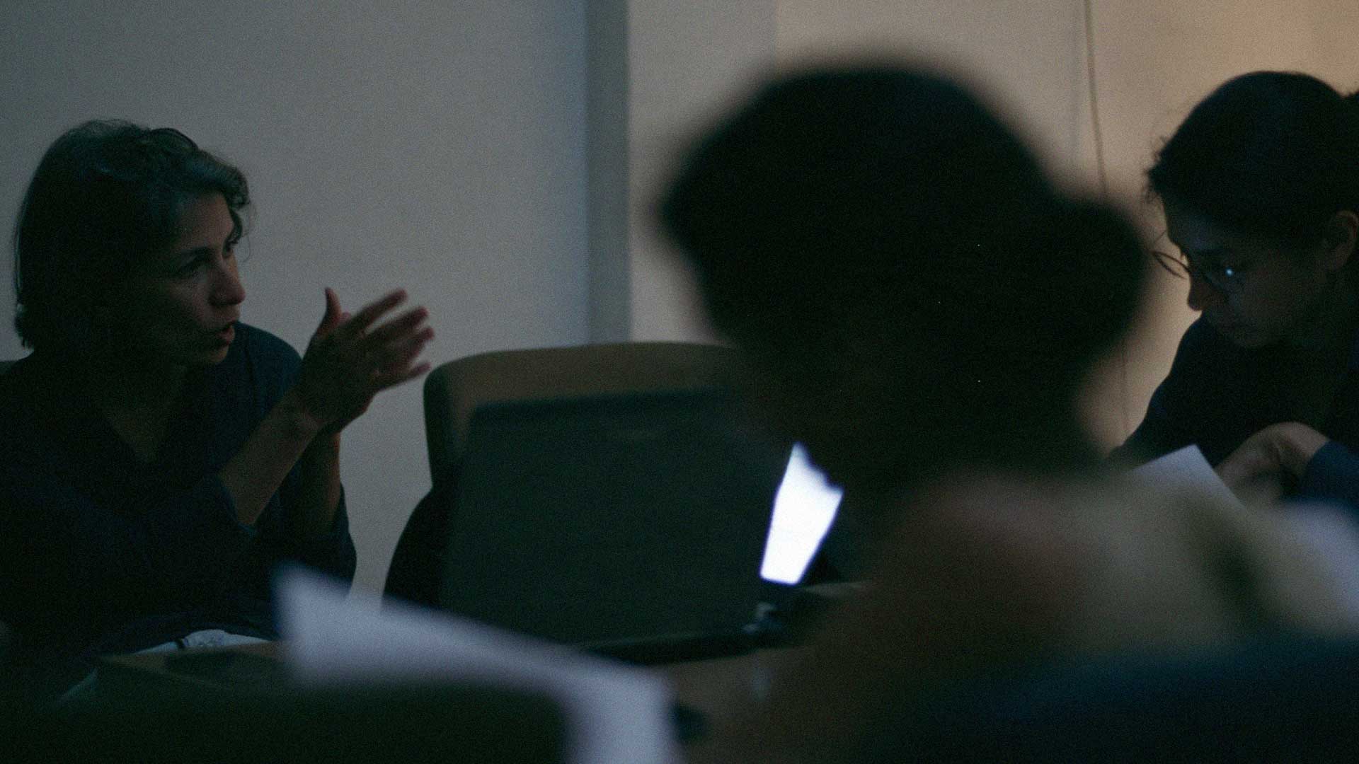 A team working together around a laptop in a low-lit studio